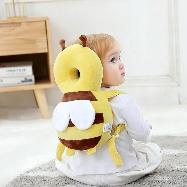 baby wearing bee head protector backpack while sitting on the floor